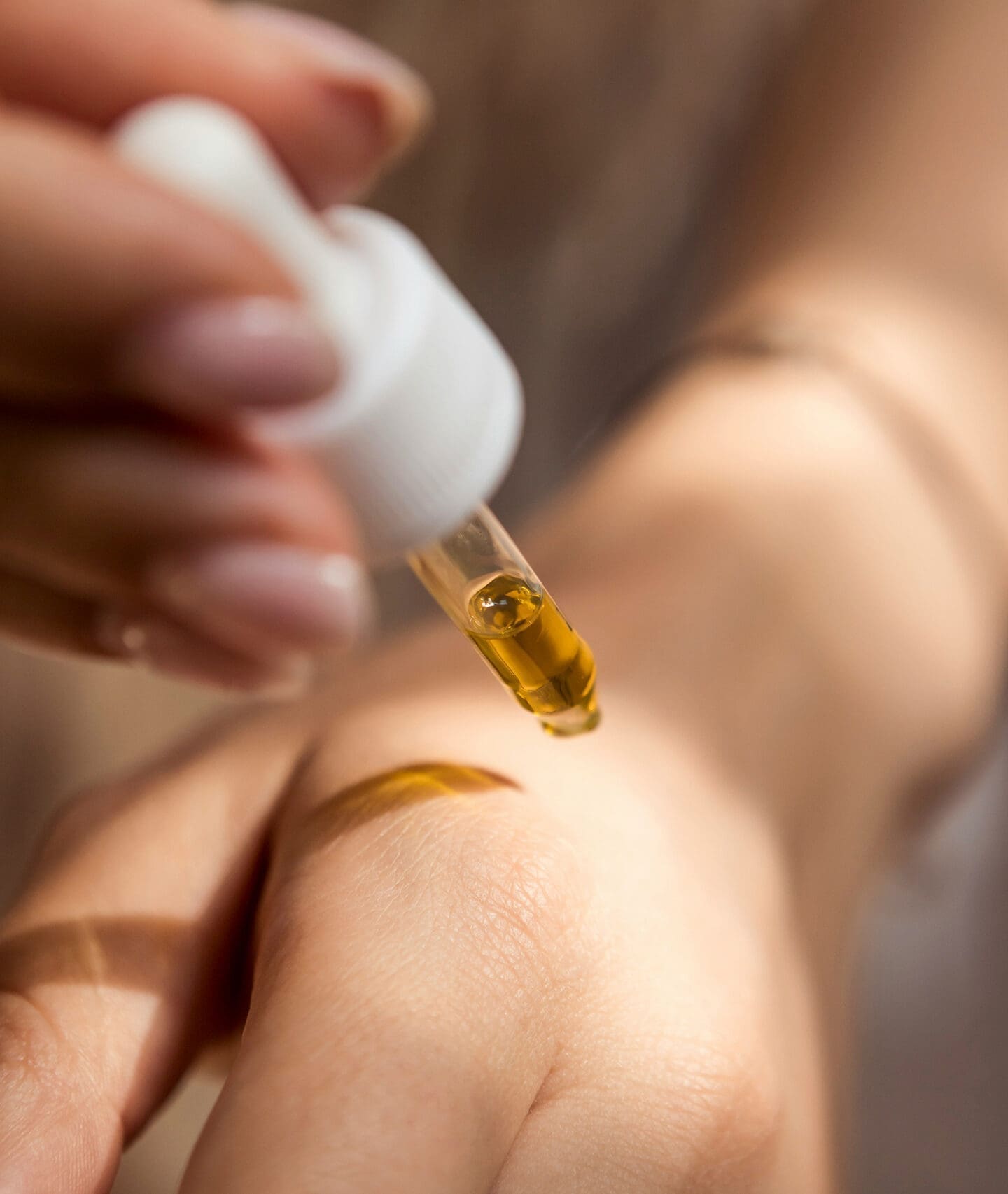 Dropper applying skincare oil to hand